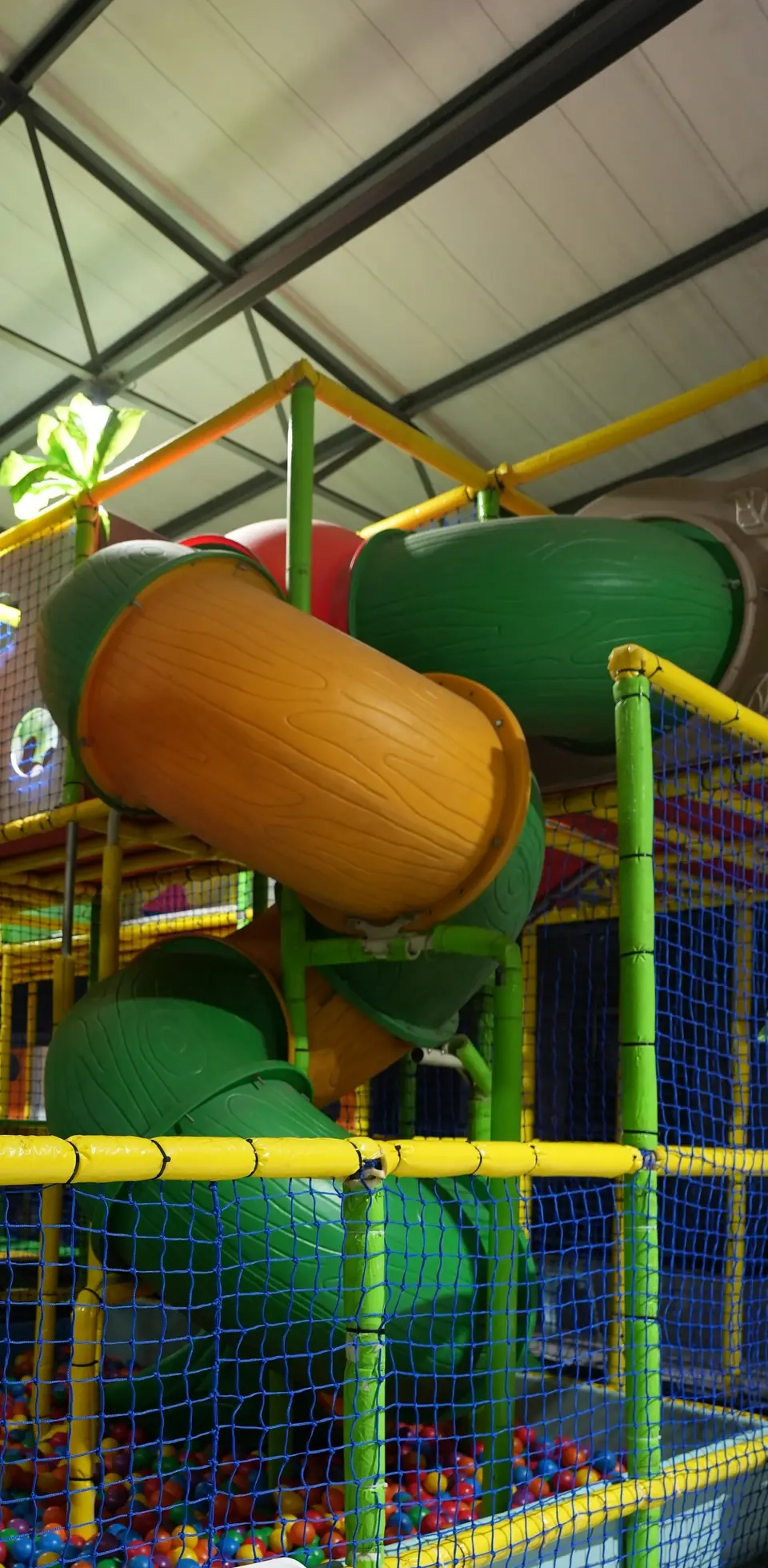 Jungle gym tube slides in orange and green above a ball pit at Jump Trampoline Park, Harare