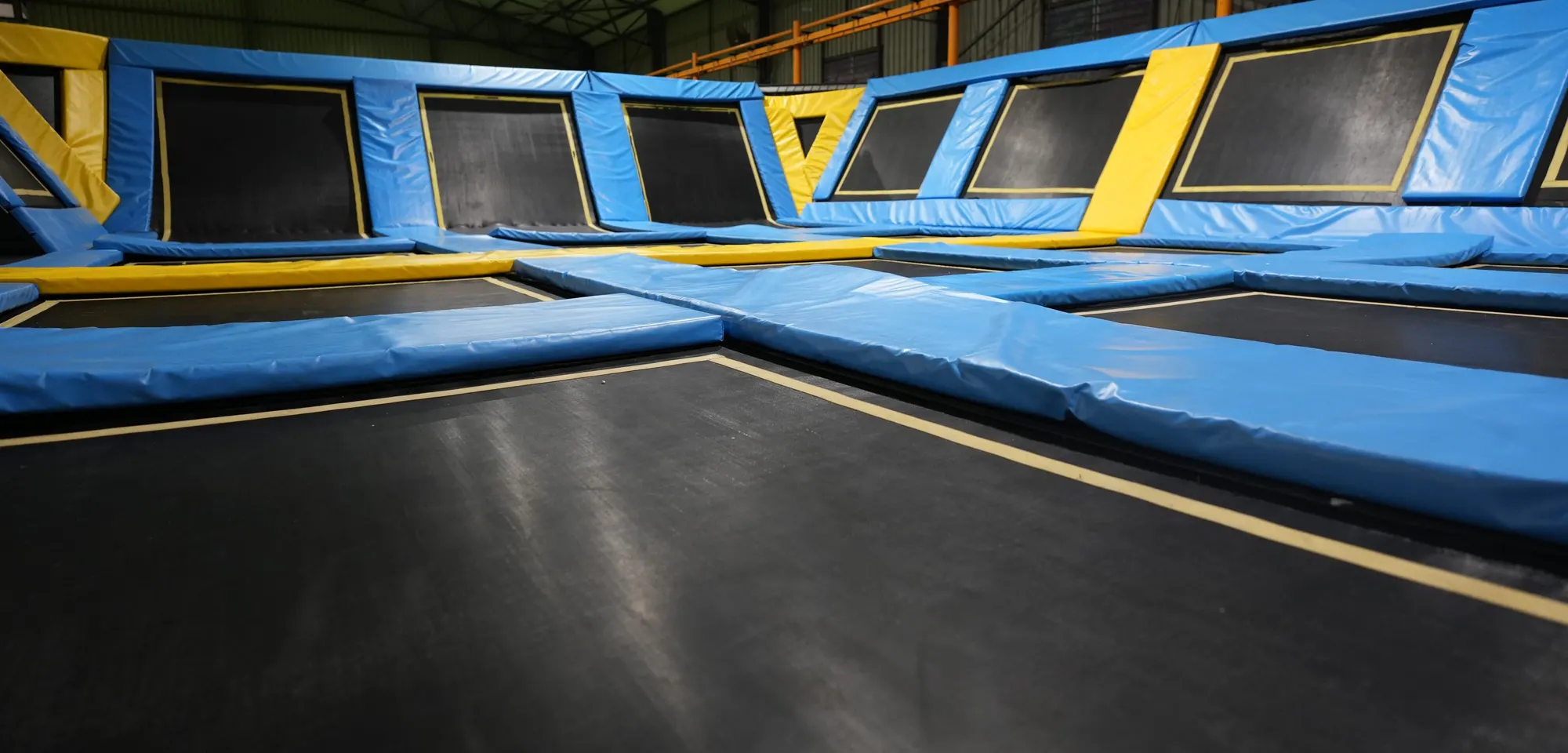Blue dodgeball court with a black floor beside the wall run at Jump Trampoline Park, Harare