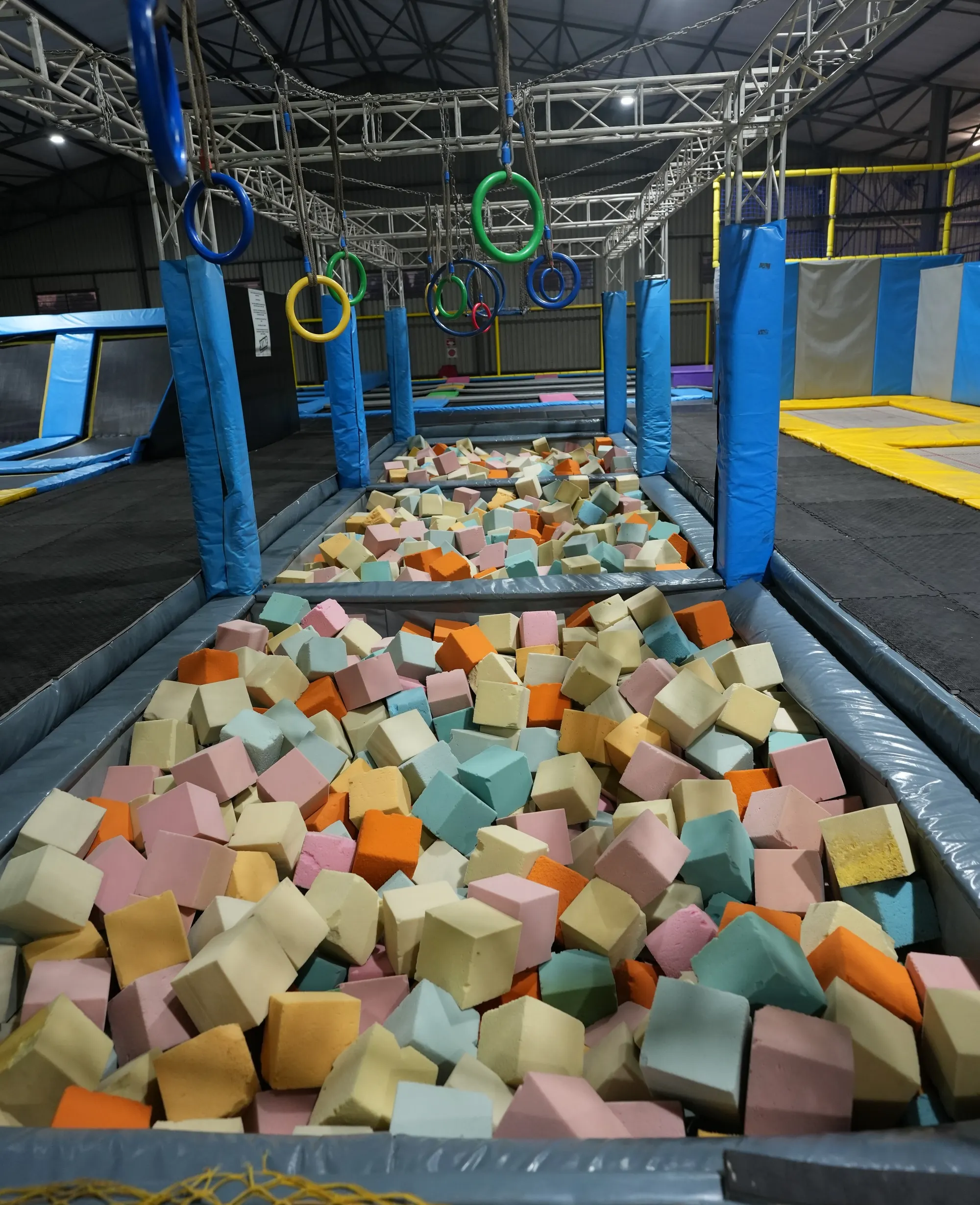 Foam pit of coloured blocks with gymnastic rings overhead at Jump Trampoline Park, Harare